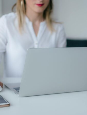 A woman working at a desk using a laptop and smartphone, exemplifying remote work.